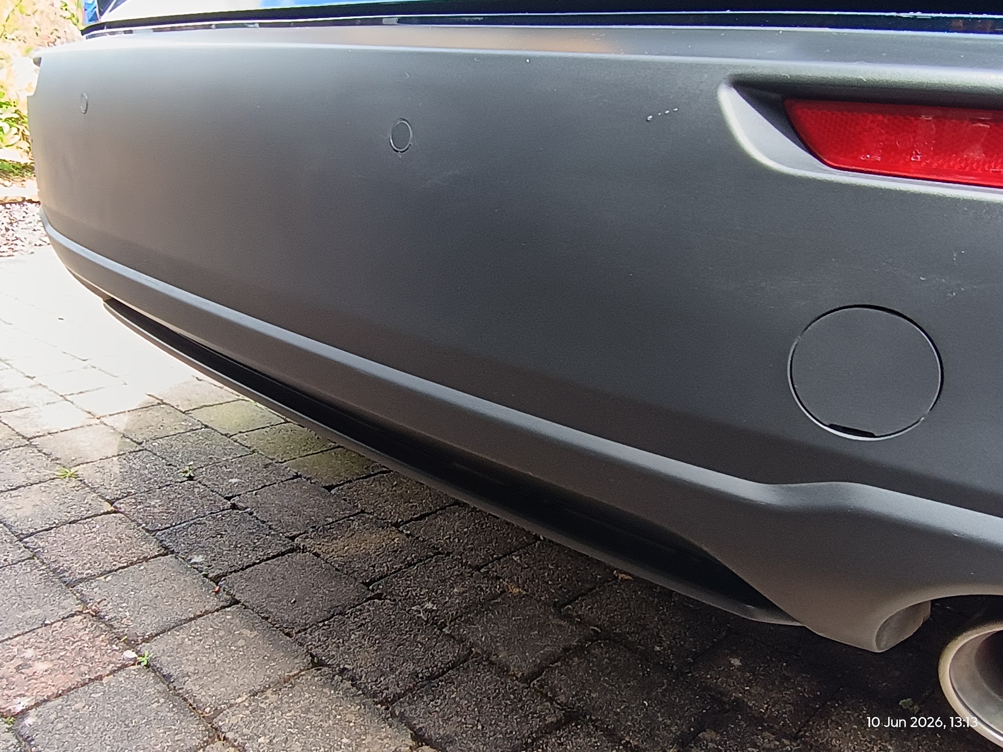 Dark grey textured rear bumper on a block paved drive