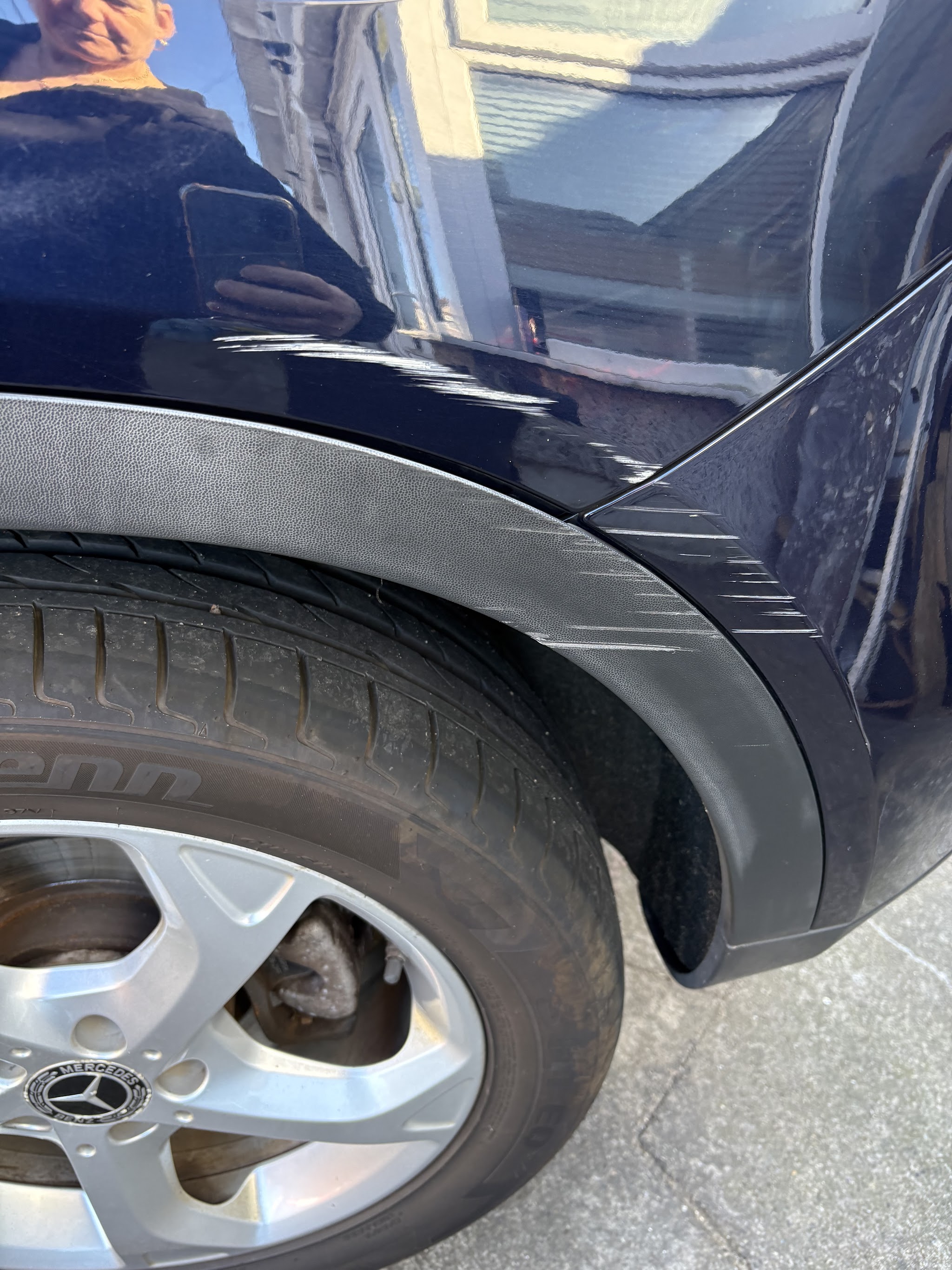 Rear wheel arch and quarter panel of a dark blue Mercedes
