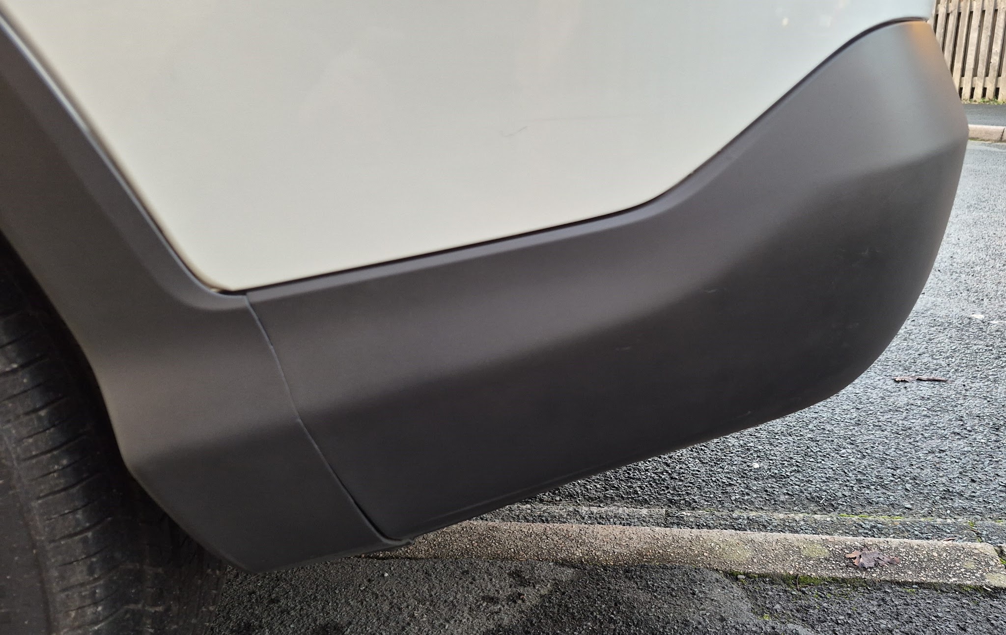 White car with a grey textured rear bumper corner