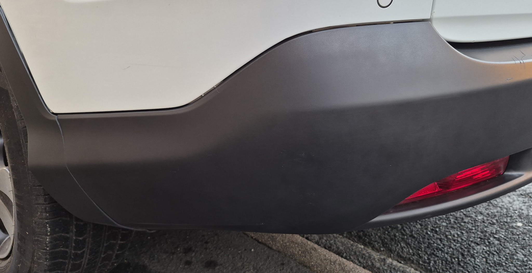 White car with a grey textured rear bumper